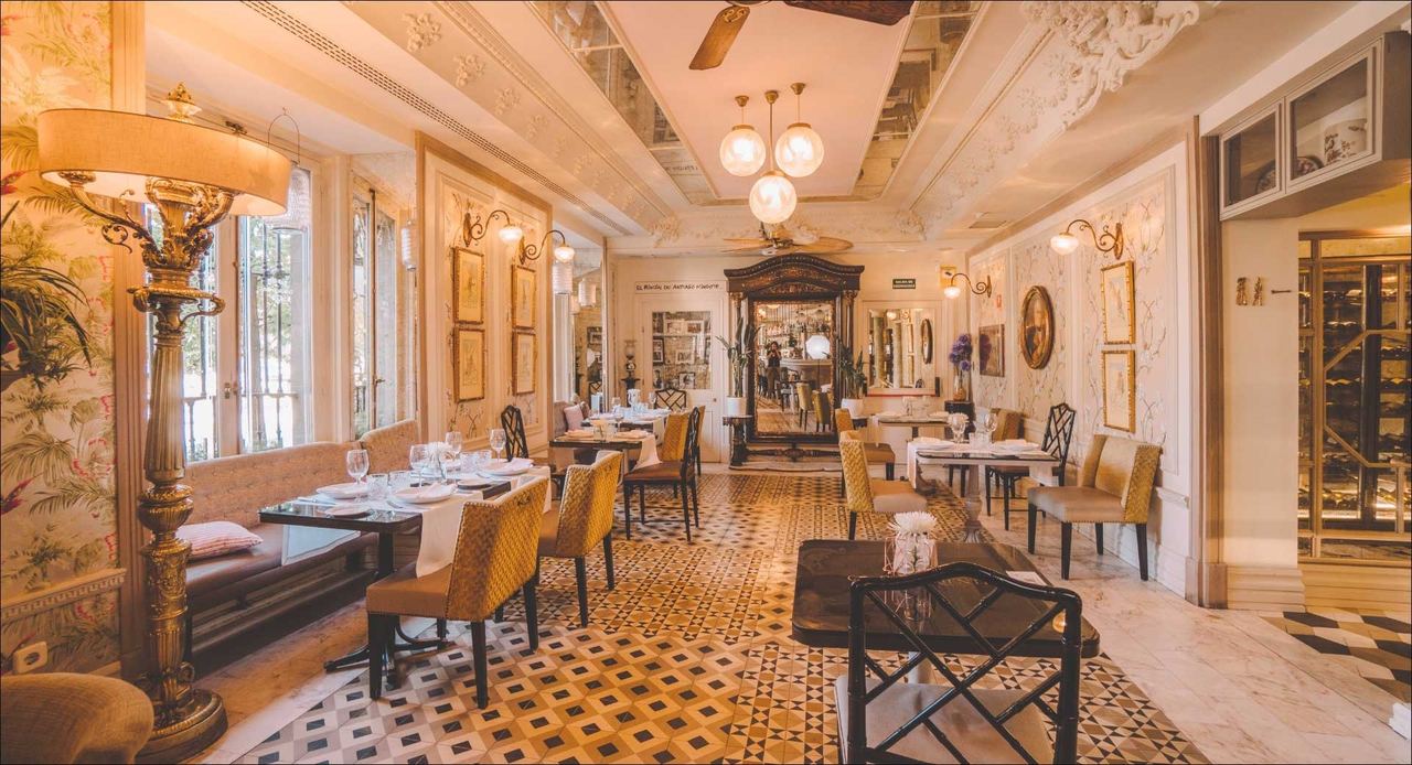 The long dining room of Café de Oriente, with globe lamps and a patterned tiled floor
