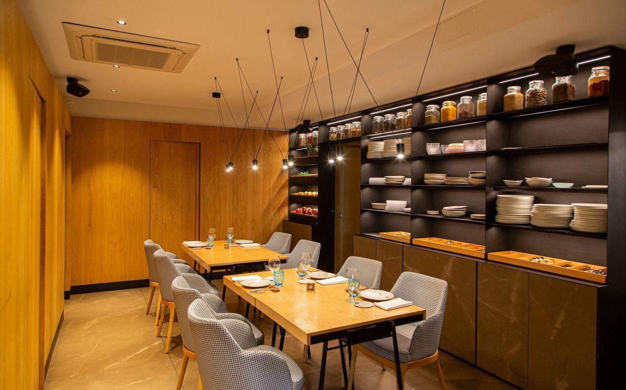 A dining room at Estimar Madrid, with wooden walls and shelves of preserves