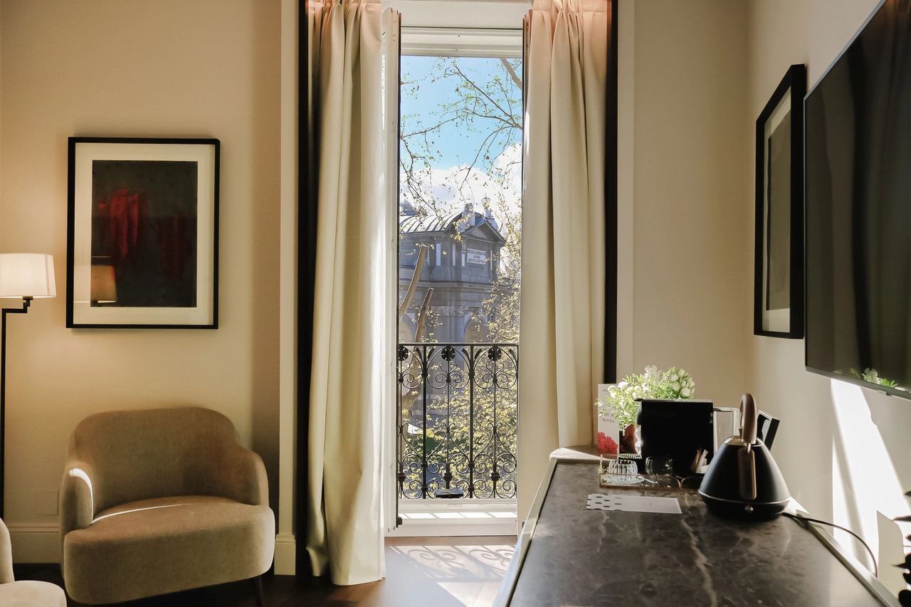 A room at Hospes Puerta de Alcalá, its balcony open over the trees
