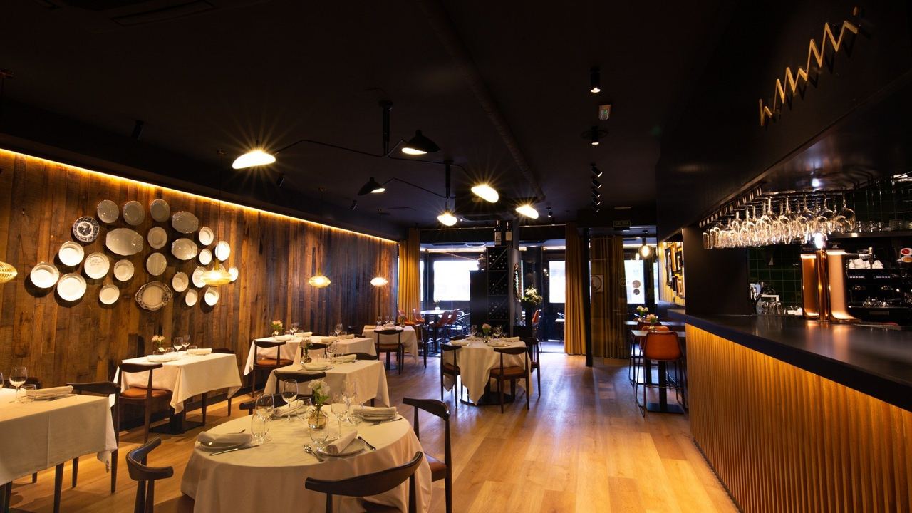 The dining room at La MaMá, with wooden walls, a wall of plates and a long bar
