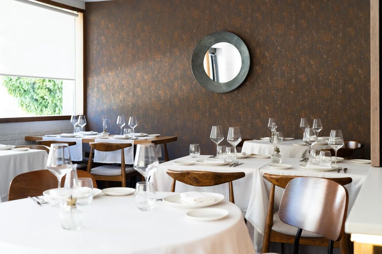 The dining room at Quinqué, with white tablecloths and a round mirror