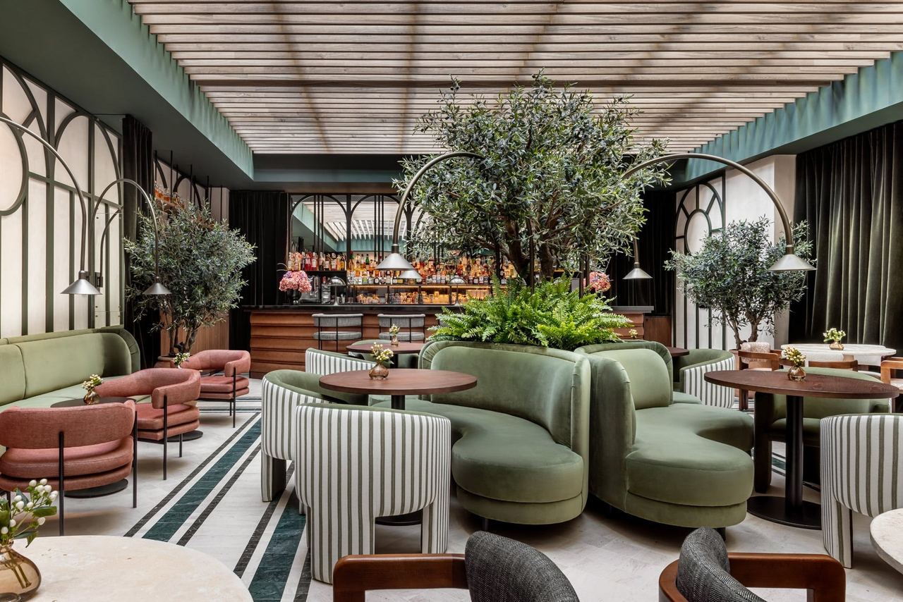 The bar and lounge of Tótem Madrid, with green velvet banquettes and olive trees