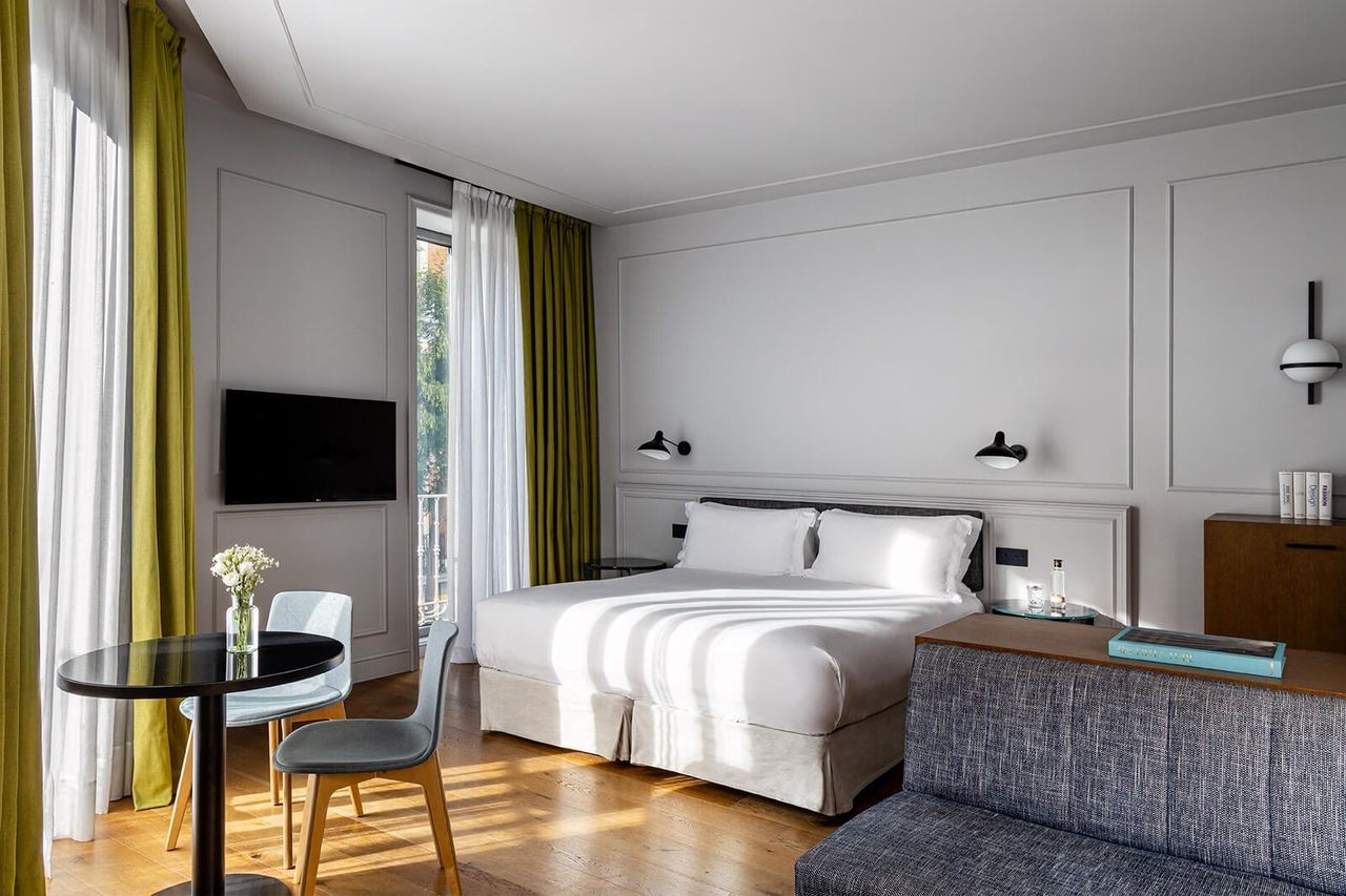 A guest room at Tótem Madrid, with white panelling and a balcony